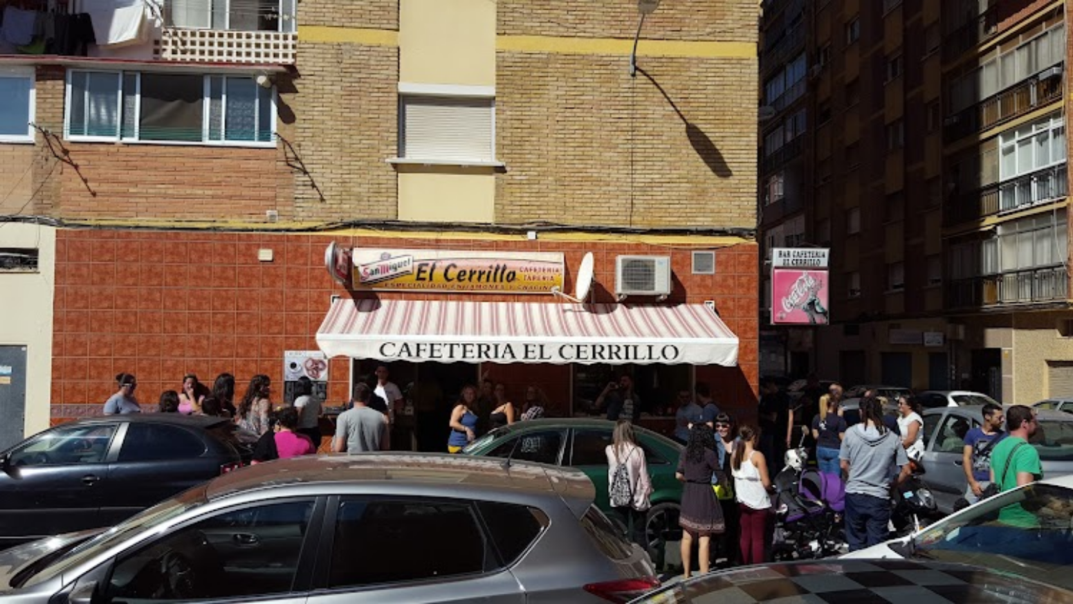 Vista de la fachada de Cafetería El Cerrillo con su toldo y personas en el exterior